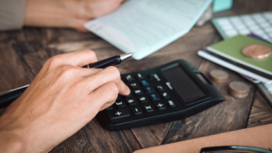 Empresário de restaurante concentrado analisando finanças com calculadora e documentos sobre a mesa, planejando a renegociação de dívida ativa para redução de custos.